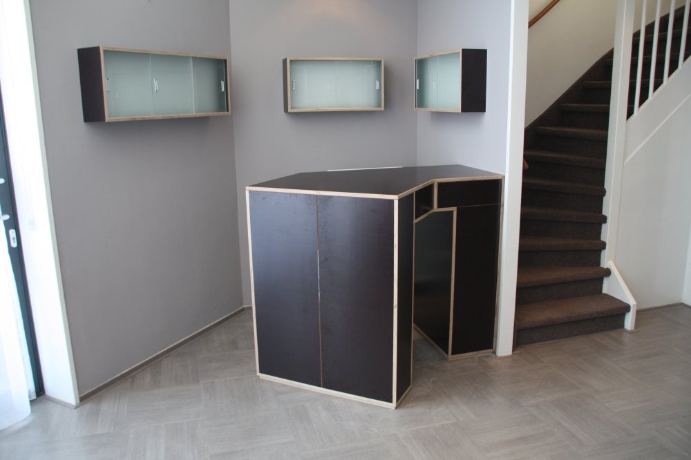 Bar en tv-meubel in één: een hoekmeubel van donker plaatmateriaal met lichte houten randen | maatwerk van Luc en Roel, Rotterdam