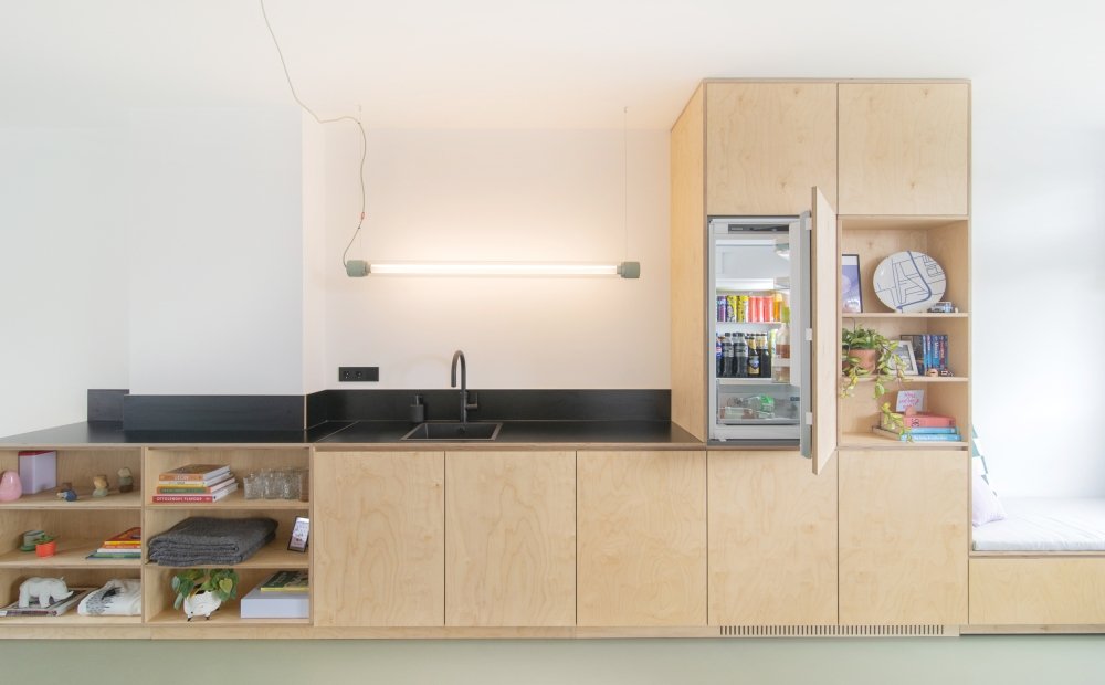 Keuken en kastenwand in een doorlopende lijn, opgebouwd uit berken multiplex met een zwart werkblad | maatwerk van Luc en Roel, Rotterdam