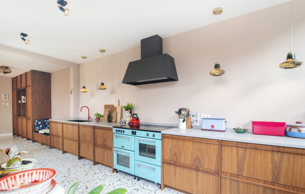 Lange keuken op maat, uitgevoerd naar ontwerp van de bewoners: warme houten fronten over de volle wand, met een ingebouwd zitbankje tussen de kasten | maatwerk van Luc en Roel, Rotterdam