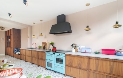 Lange keuken op maat, uitgevoerd naar ontwerp van de bewoners: warme houten fronten over de volle wand, met een ingebouwd zitbankje tussen de kasten | maatwerk van Luc en Roel, Rotterdam