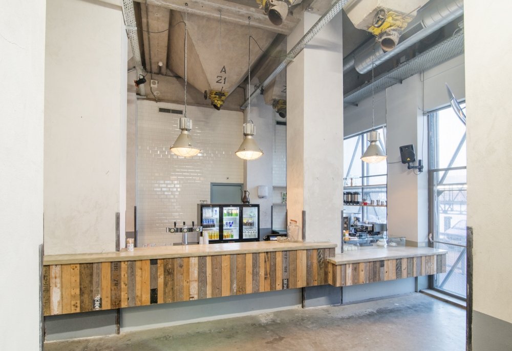 Horeca-interieur in een oud industrieel pand: bars en fronten bekleed met sloophout waar de oude stempels nog op staan | maatwerk van Luc en Roel, Rotterdam