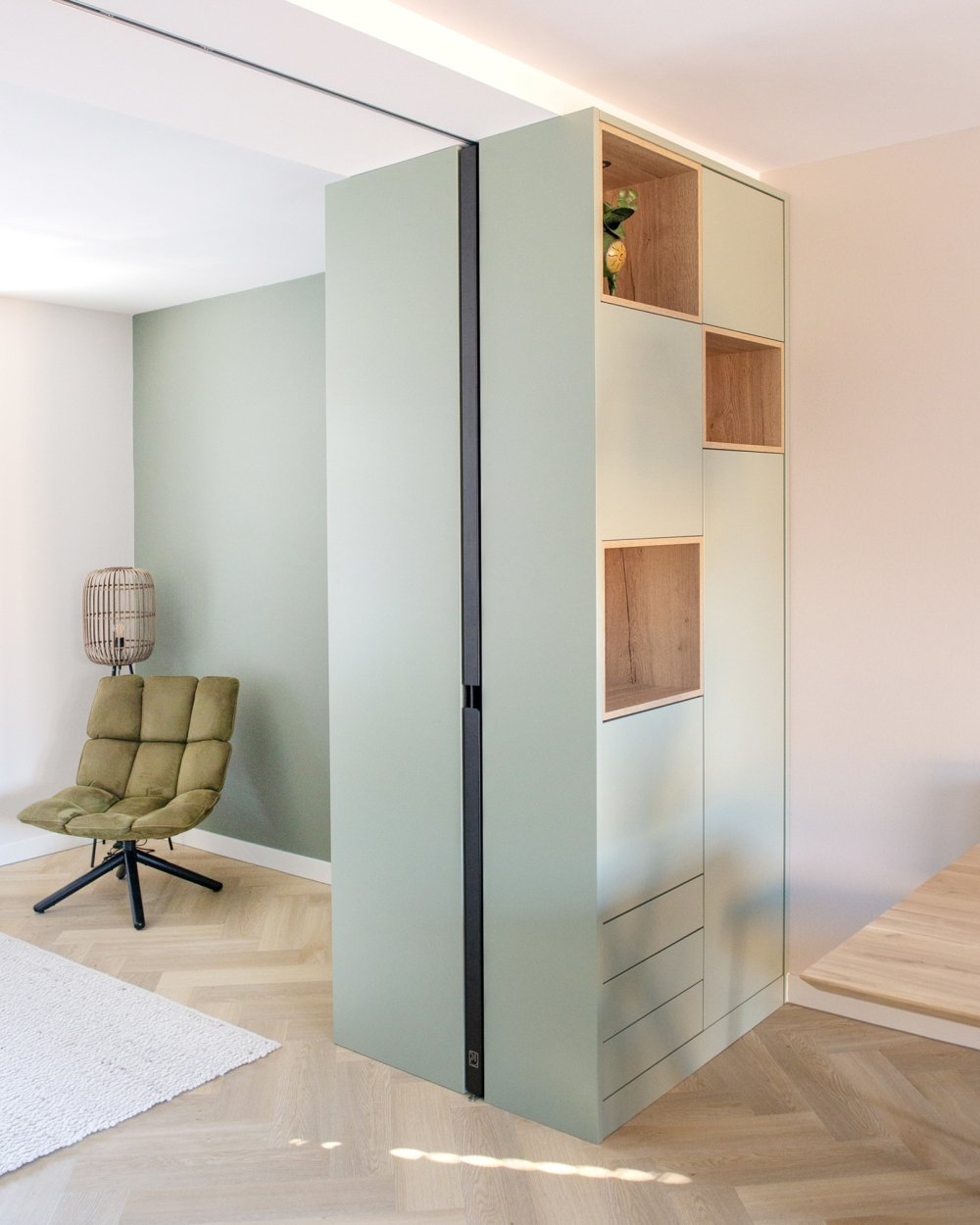 Roomdivider van gespoten MDF in zachtgroen, met open eiken nissen die de kastwand luchtig houden | maatwerk van Luc en Roel, Rotterdam