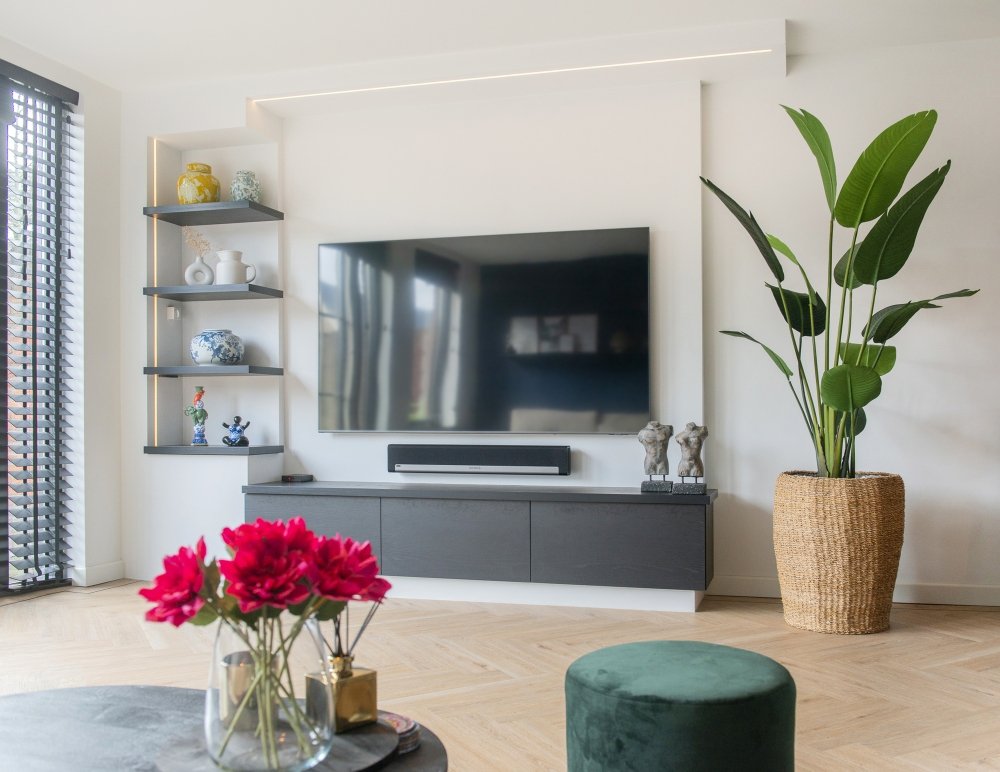 Geen kast maar muur: een gestucte vorm die uit de wand groeit en het meubel, de planken en de tv draagt | maatwerk van Luc en Roel, Rotterdam