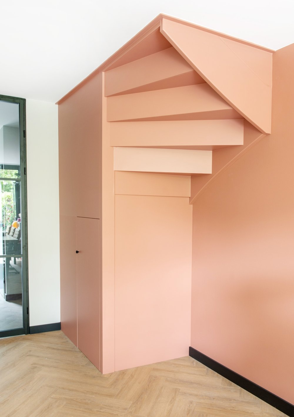 Trapkast op maat onder een draaitrap, strak gespoten in warme roze tinten | maatwerk van Luc en Roel, Rotterdam